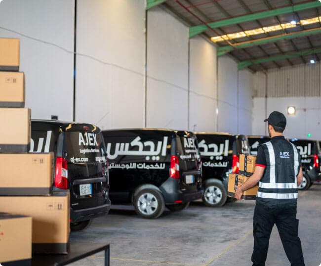 سائق توصيل ايجكس يمشي تجاه السيارة وهو يحمل الشحنات